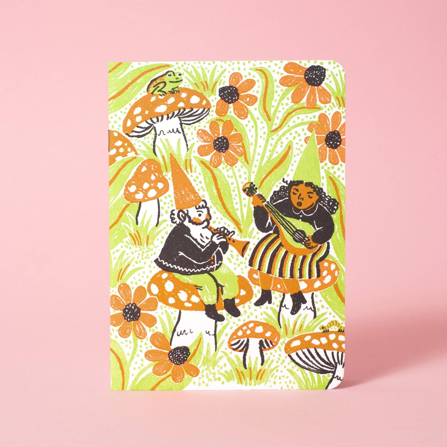 Notebook with colorful mushroom and fairy design on a pink background