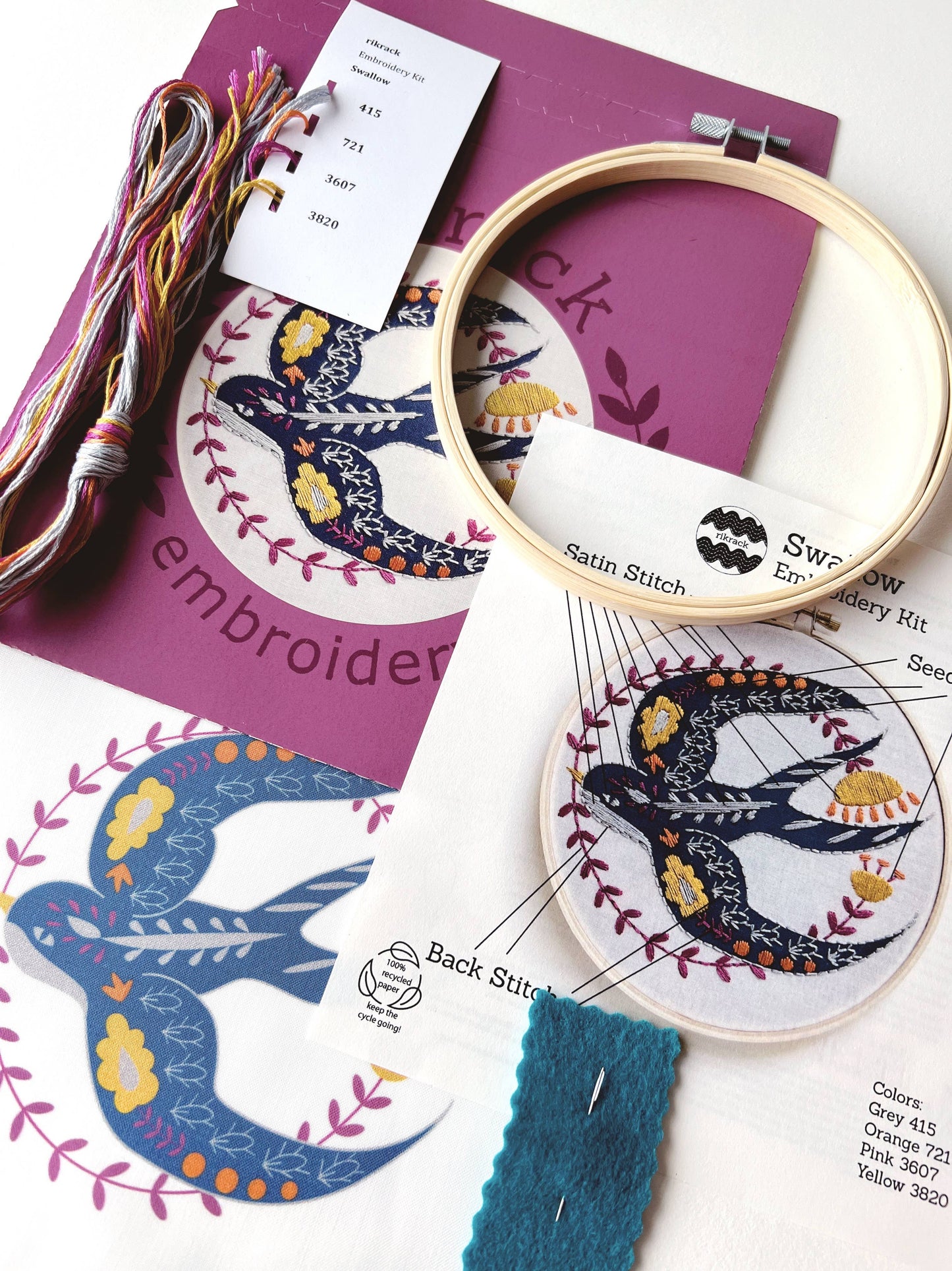 Embroidery hoop with colorful thread and pattern guide on a white background