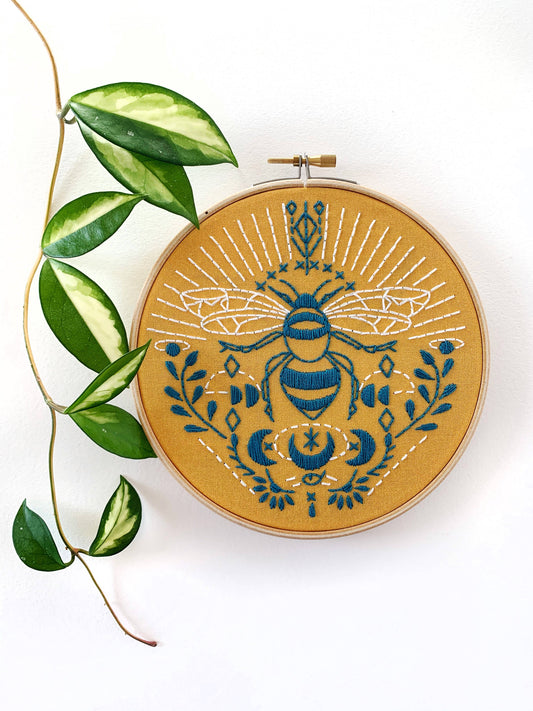 Embroidery hoop with a blue bee design on a white background