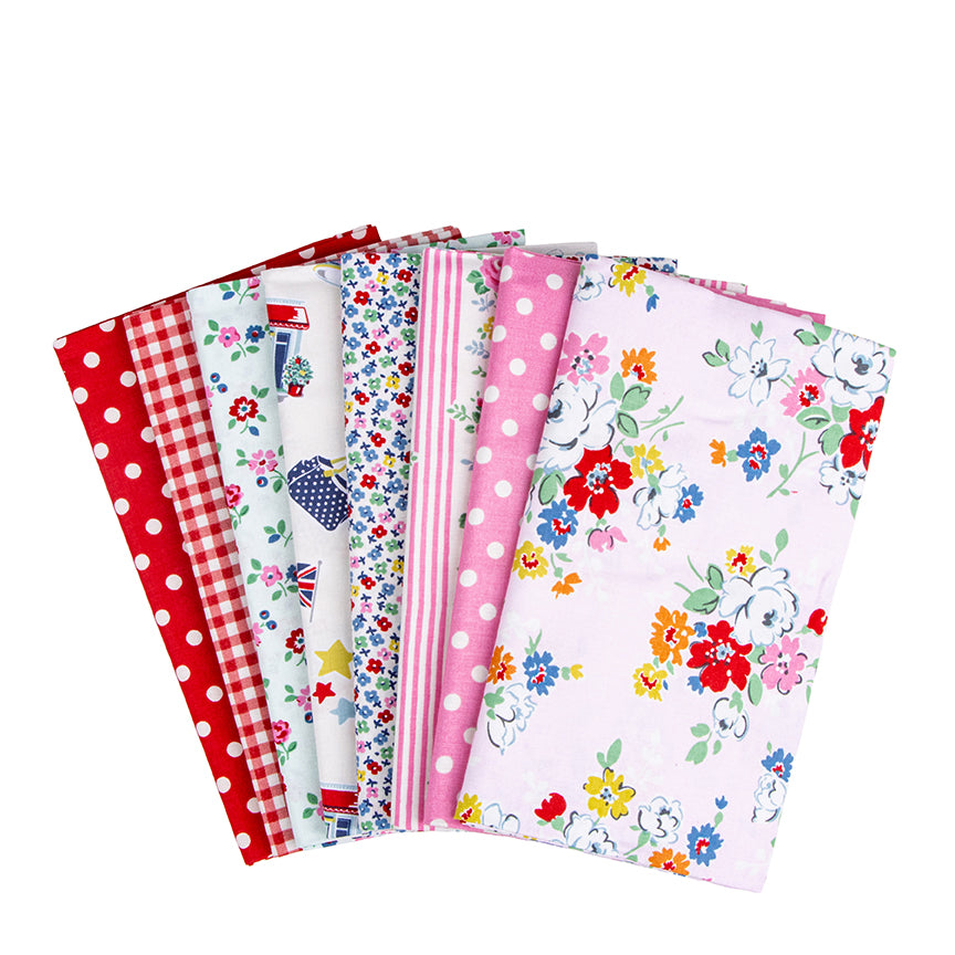 A fan arrangement of multiple fabric bolts with various patterns including pink polka dots, red gingham, multicolor florals, and blue-and-white motifs, photographed on a plain white background.