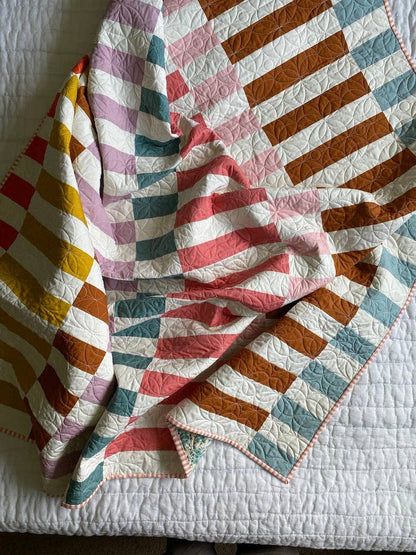 Colorful quilt with geometric patterns on a white surface