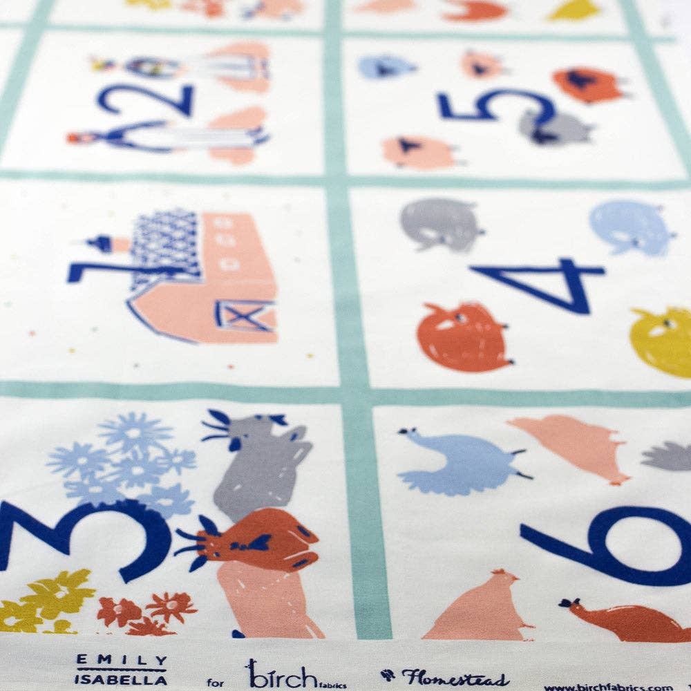 A close-up of a printed fabric or textile panel with a six-panel grid, each containing a large blue number and a small illustrated animal or object in pastel colors. The bottom edge shows the text 'EMILY ISABELLA for birch houses' and a website, indicating the product brand.