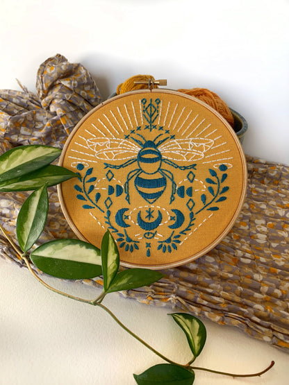 Embroidery hoop with bee design on a woven mat with leaves