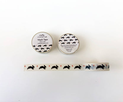 Two small round containers of washi tape with a white label printed with black rabbit silhouettes, shown above a matching strip of washi tape laid horizontally on a white background.