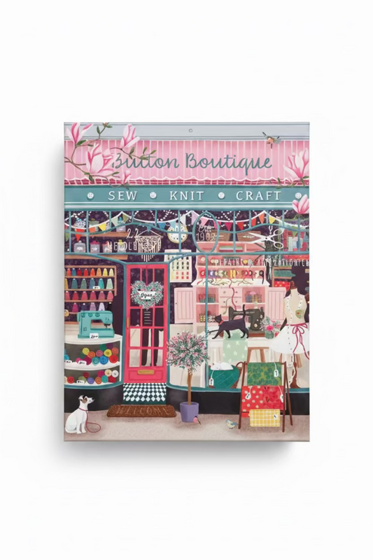 A 1000-piece jigsaw puzzle box for 'Button Boutique' by Werkshoppe, featuring a colorful, whimsical illustration of a sewing and knitting shop with a pink awning, red door, and various craft items.
