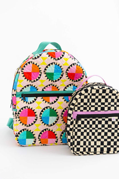 Two backpacks, large one (Archie) with a colorful geometric pattern and the small one (Violet) with a black and white checkered pattern, on a white background.