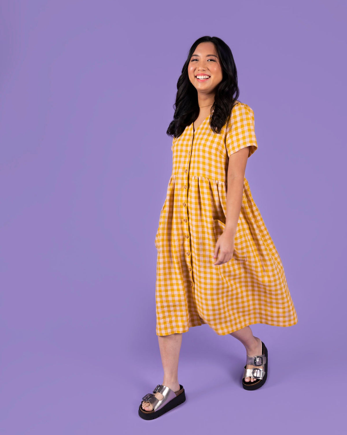 Woman wearing a yellow checkered dress on a purple background