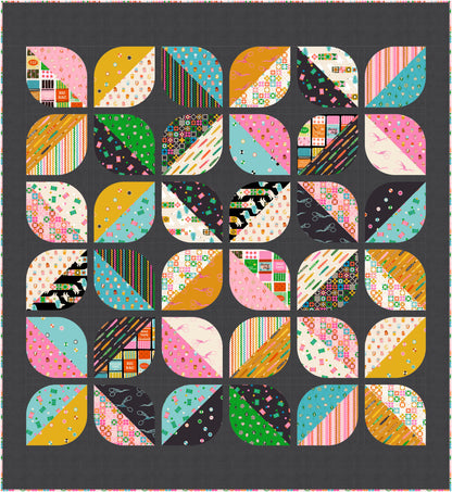 A square quilt or textile panel featuring a grid of colorful geometric and patterned blocks separated by a dark charcoal background. The individual sections include stripes, polka dots, floral prints, and abstract designs in pink, teal, mustard yellow, green, black, and white.