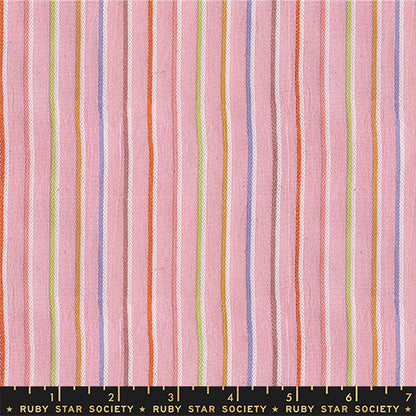 Pink striped fabric with vertical stripes in orange, purple, green, and white, shown with a Ruby Star Society ruler at the bottom for scale.