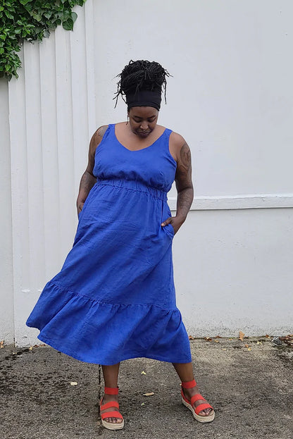Woman wearing a blue dress standing against a white wall.