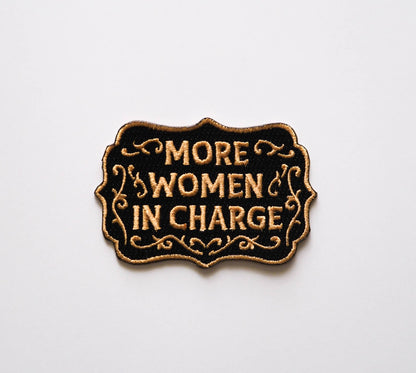 Patch with 'More Women in Charge' text on a white background