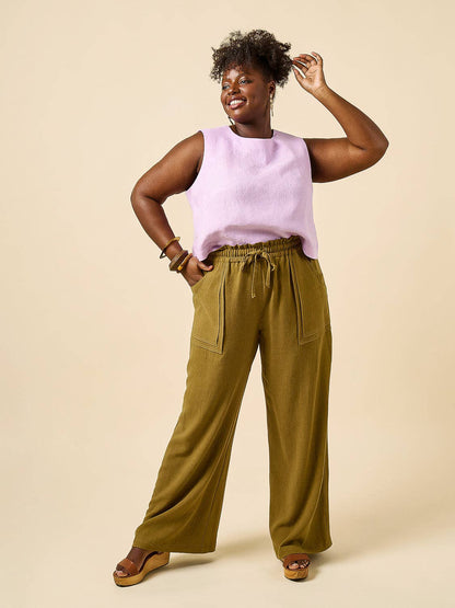 Woman wearing a light purple sleeveless top and olive green wide-leg pants on a beige background